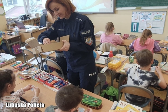 Policjantka rozdaje dzieciom obrazki w klasie.