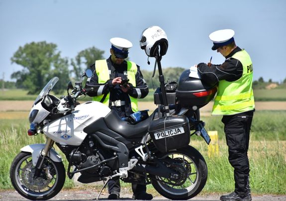 dwóch umundurowanych policjantów obok motocykla służbowego
