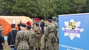 Żołnierze oraz osoby cywilne czekają w kolejce aby skorzystać z symulatora wypadków, znajdującego się na stoisku promocyjnym Policji.