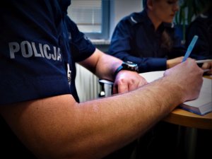 Policjanci podczas odprawy przed działaniami dokonują wpisów do notatników.