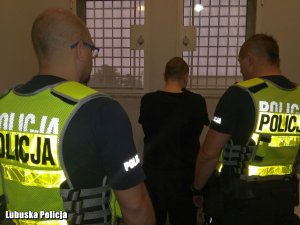 Policjanci sulęcińskiej drogówki stoją tyłem w celi wraz z zatrzymanym mężczyzną.