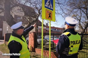 Policjanci Ruchu Drogowego stoją przed znakiem oznaczającym przejście dla pieszych w wersji fluorescencyjnej usytuowanym na ulicy Emilii Plater w Sulęcinie.