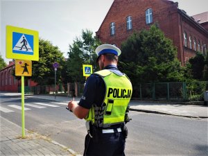 Policjant sporządzona notatkę z lustracji oznakowania przejścia dla pieszych.