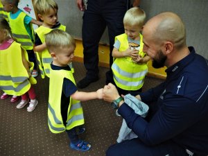 Chłopczyk przybija tak zwanego żółwika policjantowi.