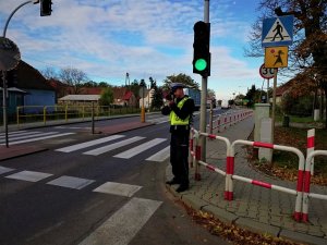 Policjant kontroluje prędkość w rejonie przejścia dla pieszych oraz sygnalizacji świetlnej.