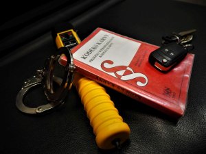 Kodeks karny, urządzenie Alcoblow, kajdanki oraz kluczyki do samochodu.