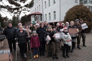 Wolontariusze Raj Paczki wraz z policjantami stoją przed Domem Pomocy Społecznej w Tursku.