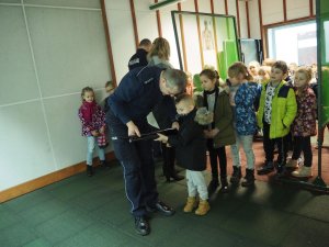 Policjant wraz z chłopcem podczas treningu bezstrzałowego. Na drugim planie reszta przedszkolaków.