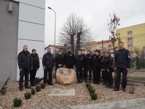 Policjanci wraz z uczniami pozują do wspólnego zdjęcia pamiątkowego przed kamieniem upamiętniającym 100. rocznicę powstania Policji Państwowej.