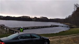 Policjant sprawdzający plaże przy jeziorze pod kątem grupujących się osób.