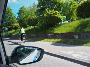 Rowerzysta w odblaskowej kamizelce jedzie drogą dla rowerów.