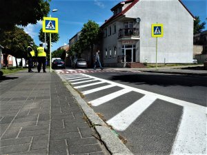 Policjanci stoją przy oznakowanym przejściu dla pieszych.