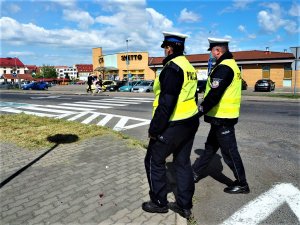 Policjanci w patrolu pieszym kontrolują przestrzeganie przepisów w okolicy przejścia dla pieszych.