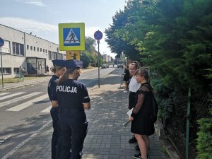 Policjantki wręczają uczniom odblaskowe zawieszki w rejonie szkoły.