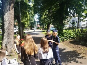 Policjantki wręczają uczniom odblaskowe zawieszki.