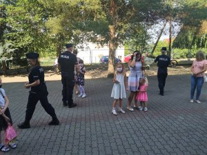 Policjanci wręczają uczniom szkoły podstawowej odblaskowe zawieszki.