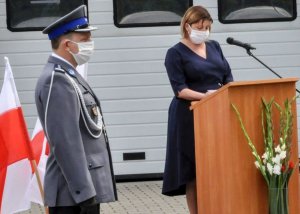 Na pierwszym planie szef sulęcińskich policjantów w galowym mundurze. W tle osoba odczytująca rozkazy przy mównicy, obok stojak z biało-czerownymi flagami.