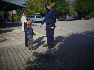 Policjant wręcza chłopcu odblaskową opaskę.