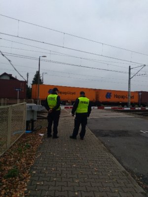 Policjant i funkcjonariusz Służby Ochrony Kolei stoją przy rogatkach