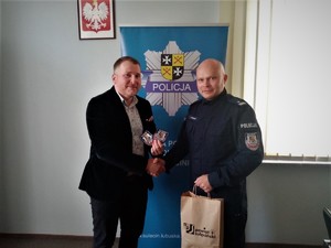 Od lewej Starosta Sulęciński podaje dłoń Komendantowi Powiatowemu Policji w Sulęcinie wręczając torbę z naszywkami. W tle roll up sulęcińskiej jednostki.