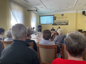 Seniorzy podczas wykładu podkomisarza Przemysława Stankiewicza. Ujęcie wykonane zza pleców osób siedzących.