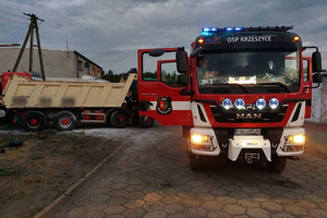 Wóz bojowy Ochotniczej Straży Pożarnej w Krzeszycach. W tle pojazd ciężarowy po ugaszeniu pożaru tylnego koła.
