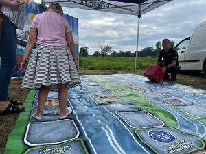 Dziewczynka pod okiem policjanta grę w wielkoformatową grę &quot;Bezpieczni na drodze z Policją&quot;.