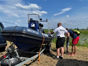 Policyjny wodniak prezentuje zainteresowanym osobom łódź policyjną.