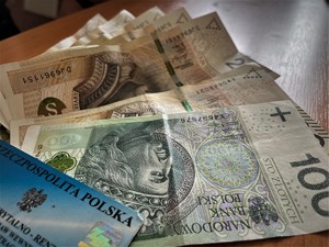 Na stole leżą pieniądze w banknotach 100 i 200 złotowych oraz legitymacja emeryta.