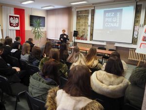 Policjantka prowadzi wykład dla młodzieży. Uczniowie siedzą tyłem do zdjęcia.