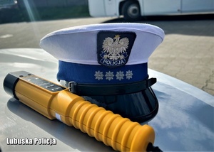 Urządzenie Alcoblow leży na masce radiowozu obok czapki policjanta ruchu drogowego.