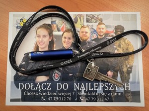 Ulotka promująca służbę w sulęcińskiej Policji, na której leży smycz z brelokiem oraz kluczem do mieszkania.