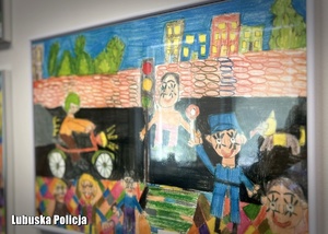 Rysunek dziecka przedstawiający policjantów oprawiony w ramce i powieszony na ścianie.