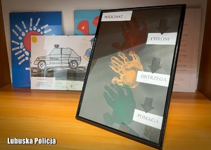 Prace plastyczne dzieci oprawione w ramkach, stojące na półce.