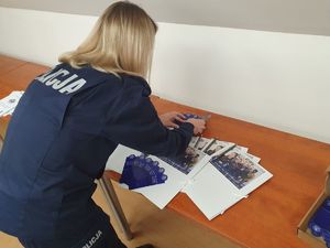 Policjantka rozkłada na stole teczki dla kandydatów do służby w Policji.