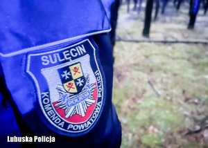 Emblemat sulęcińskiej Policji na kurtce policjanta. W tle widać las.