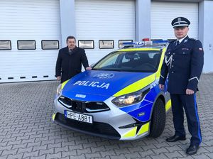 Wójt Gminy Słońsk i Komendant Powiatowy Policji w Sulęcinie stoją przy oznakowanym radiowozie.