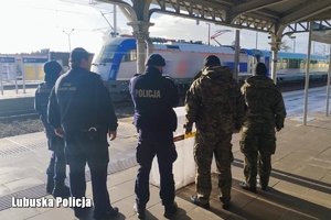 Policjant, Strażnicy Ochrony Kolei oraz Straży Granicznej patrolują dworzec kolejowy.