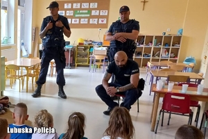 Policjant oraz strażnicy kolejowi prowadzą spotkanie edukacyjne dla przedszkolaków.