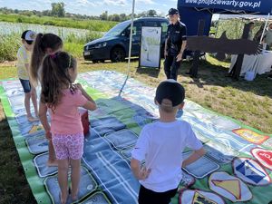 Policjantka nadzoruje rozgrywki na wielkoformatowej grze &quot;Bezpieczni na drodze z Policją&quot; podczas festynu.