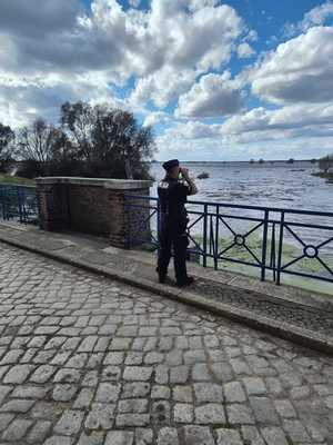 umundurowany policjant obserwuje przez lornetkę wodę na rozlewiskach Warty