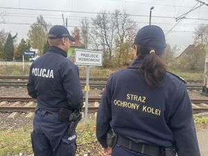 Policjant i funkcjonariuszka Straży Ochrony Kolei patrolują infrastrukturę kolejową.