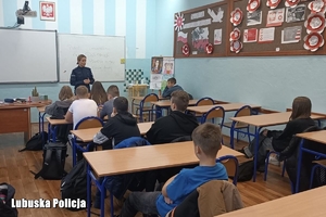 Policjantka prowadzi zajęcia edukacyjne z uczniami w gabinecie szkolnym.