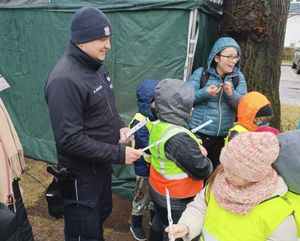 Dzielnicowi rozdaje odblaski dzieciom.