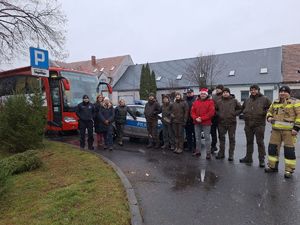 Policjanci, strażacy i pracownicy Nadleśnictwa pozują do wspólnego zdjęcia na tle radiowozu i krwiobusa.