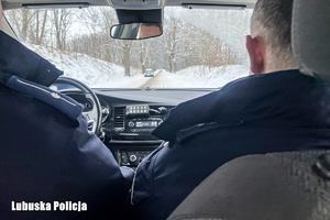 Policjant wewnątrz radiowozu, w tle ośnieżona droga.