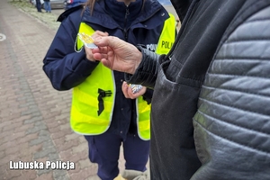 Policjantka wręcza odblask seniorowi.