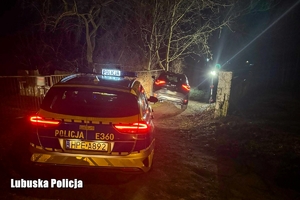 Radiowóz i odzyskany pojazd Kia Sportage na drodze szutrowej w porze nocnej.