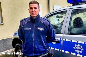 Policjant stoi przy radiowozie.