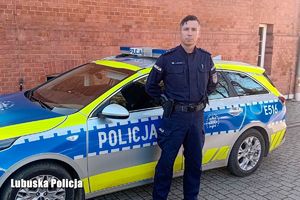 Policjant stoi przy radiowozie.